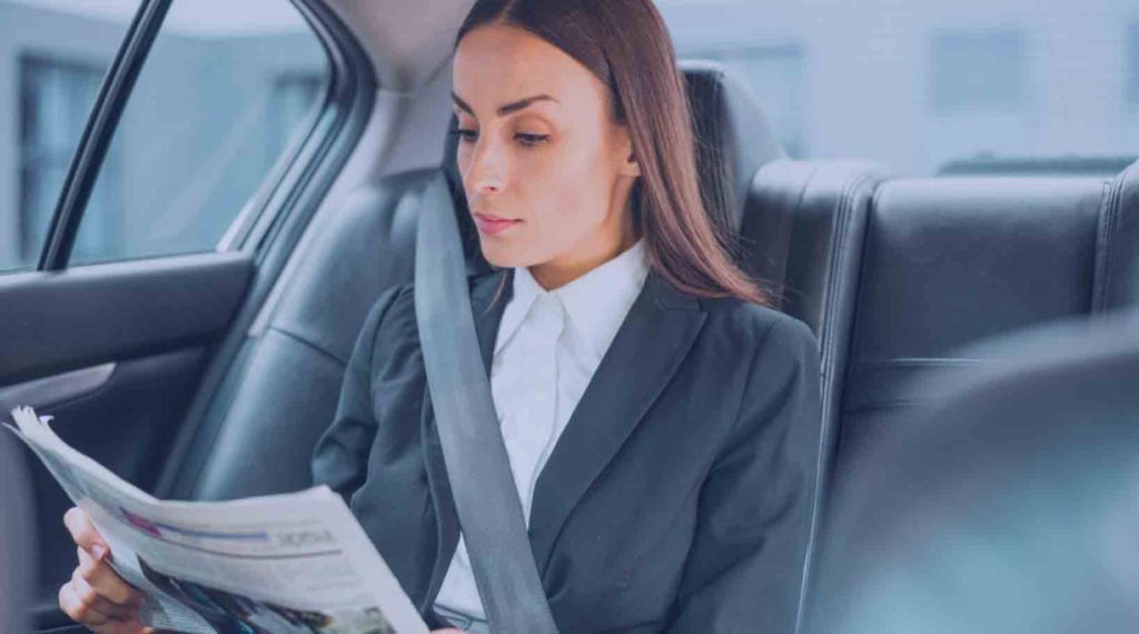 Girl sitting in a car reading newspaper